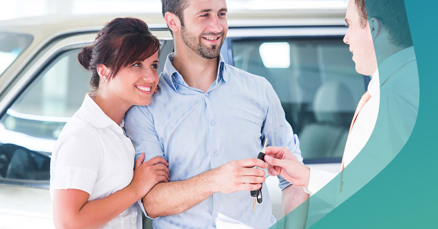 Woman and man excited about purchasing car and car insurance are handed the keys to their new car.