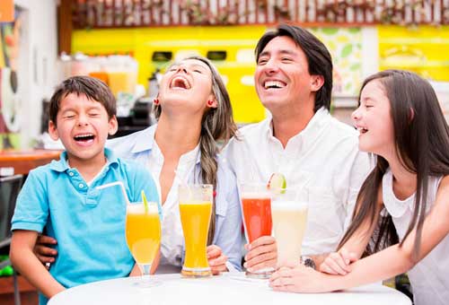 Man in white shirt with family enjoying healthy juice drinks. Life insurance.
