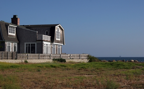 Two story home with Homeowners Insurancelarge windown overlooking field of green grass clear blue skies in background no clouds bright sunny day