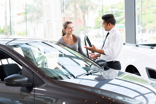woman negotiating car price at dealership after college graduation