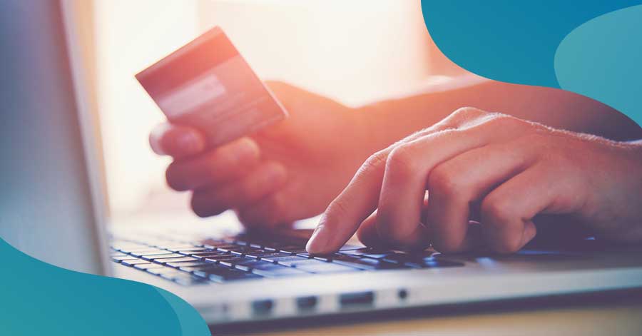 Close up of hands at a laptop keyboard paying a bill with credit card. How to save on car insurance.