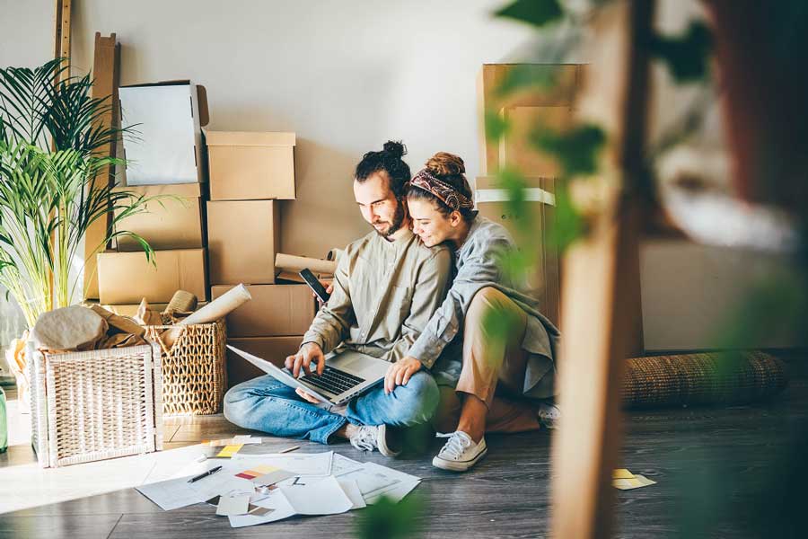 Couple in a house together looking at life insurance policies on a laptop.