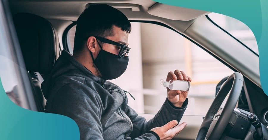 Driver in mask applying hand sanitizer