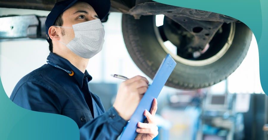 mechanic wearing mask looking at car